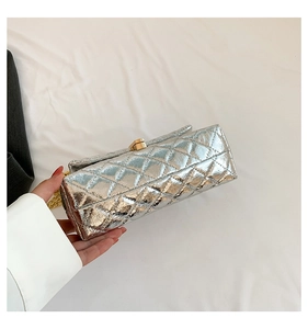 Détail d'un sac bandoulière argenté matelassé avec fermoir doré et bandoulière en chaîne