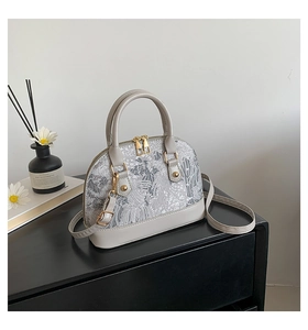 Detail of grey shell-shaped handbag with mountain pattern print and gold hardware