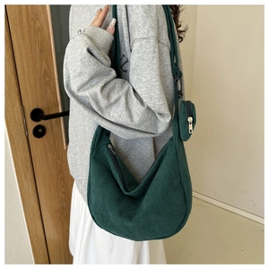 Detail of dark green corduroy crescent crossbody bag with a round mini pouch accessory