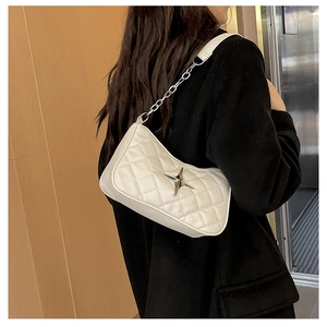 Detail of white quilted crossbody bag with silver star hardware and chain strap