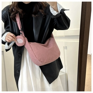 Pink corduroy crossbody bag with matching round coin purse shown on black leather jacket