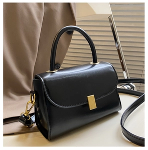 Detail of minimalist black leather crossbody bag with elegant gold metal buckle closure