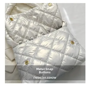 Détail du fermoir magnétique doré sur le sac matelassé blanc à finition brillante