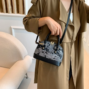 Fashionable shell-shaped handbag with embroidery and gold hardware shown on a model