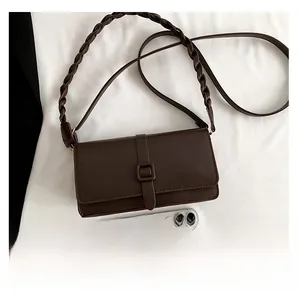 Detail view of brown PU leather shoulder bag with woven strap and smartphone for size scale