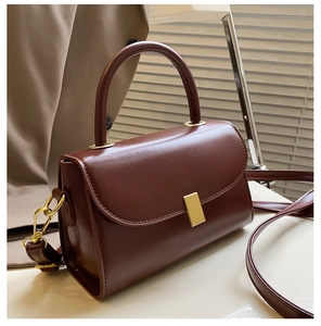 Close-up of brown textured leather handbag featuring golden metallic buckle and hardware