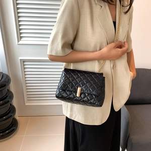 Sac à bandoulière matelassé noir avec chaîne dorée et fermoir métallique sur modèle