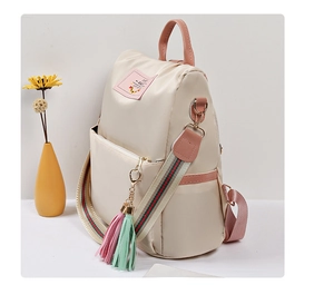 Détail du sac à dos en nylon crème avec finitions en cuir rose et sangles rayées