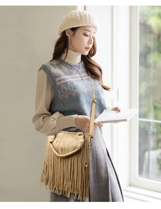 Detail of camel fringe shoulder bag with long tassels and adjustable strap in soft light