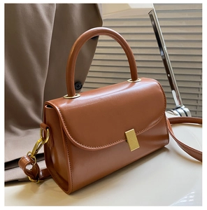 Close-up of caramel leather handbag featuring elegant gold metal buckle and smooth texture