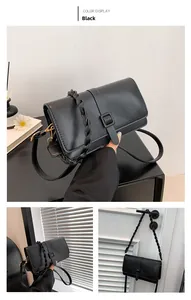 Detail of matte black leather square bag showing textured weaving handle and gold buckle hardware