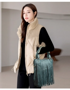 Close-up of a dark green handbag featuring decorative tassels and metallic stud details
