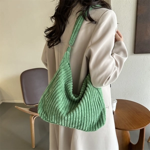 Green corduroy tote bag shown on shoulder, highlighting its soft texture and large capacity