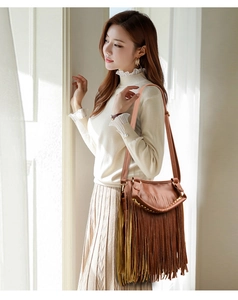 Brown tassel crossbody bag with golden hardware shown as lifestyle model shot