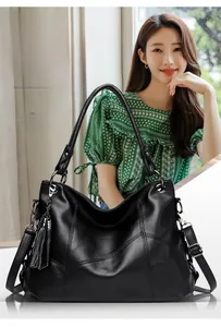 Detail of black pebbled PU leather tote bag featuring a tassel charm and sturdy stitching