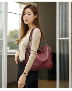Detail of burgundy leather tote bag featuring a V-shaped seam and pebble grain texture