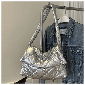 Détail du sac cabas matelassé argenté avec motif de losanges sur une veste en denim bleu