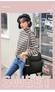 Détail du sac à dos en nylon noir avec poignées roses et pompon coloré dans la rue
