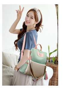 Détail du sac à dos bicolore vert et beige avec bandoulière rayée et pompon