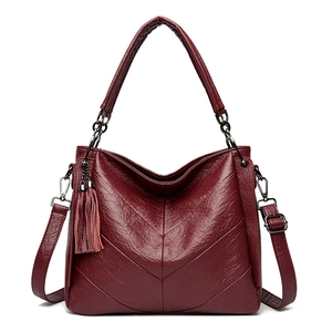 Detail of wine red crossbody bag with V-shaped stitching and side tassel charm
