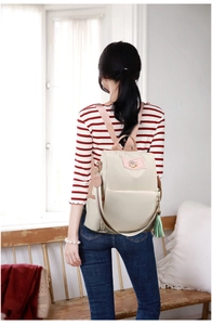 Vue détaillée d'un sac à dos Oxford beige antivol avec poignées roses porté par un modèle