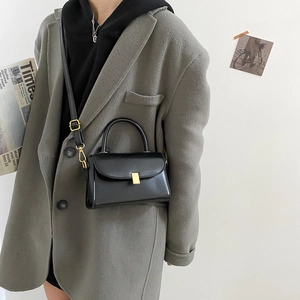 Minimalist black leather crossbody bag with gold lock buckle and adjustable strap