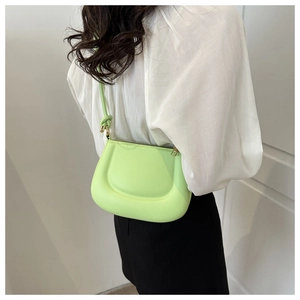 Détail d'un sac hobo vert fluo porté en bandoulière sur un mannequin en chemise blanche
