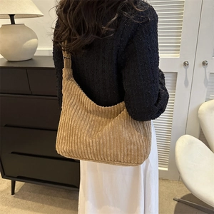 Detail of light brown corduroy tote bag showing soft ribbed texture on a model shoulder