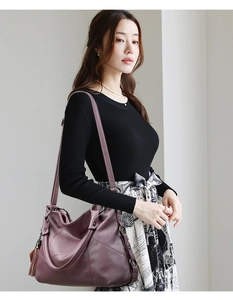Detail view of purple lychee pattern PU tote bag with tassel charm worn by a model