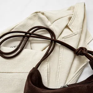 Detail of dark brown suede shoulder bag with soft knotted strap and minimalist design