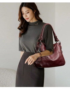 Detail view of burgundy leather tote bag with elegant tassel charm and metallic zipper