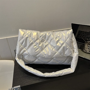 Sac bandoulière matelassé argenté avec texture bouffante et large sangle sur bureau