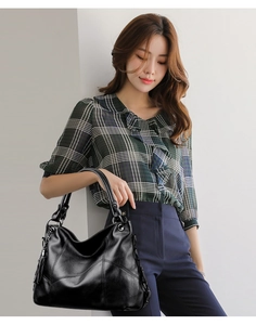 Detailed view of black PU leather hobo tote with geometric stitching and tassel detail