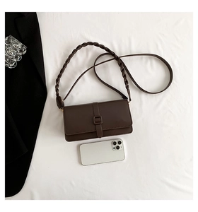 Detail view of brown leather crossbody bag with distinctive thick woven shoulder strap