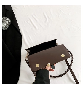 Detail of dark brown flap crossbody bag with woven strap and gold magnetic buckles