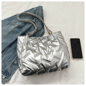 Détail d'un sac cabas argenté matelassé avec texture métallique et bandoulière en cuir