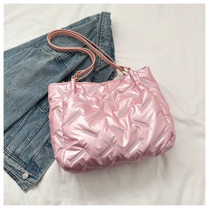 Détail du sac fourre-tout matelassé rose brillant posé sur une veste en jean bleue