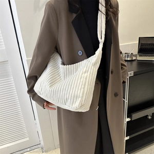 Detail of soft white corduroy tote bag showing striped texture and wide shoulder strap