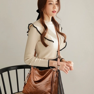 Brown quilted crossbody bag with fringe tassel and adjustable strap worn by model