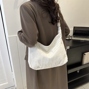 Detailed texture of white corduroy fabric on a crescent shoulder bag worn by model