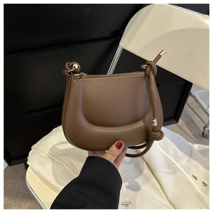 Gros plan sur le sac croissant marron avec nœud décoratif et détails en métal doré