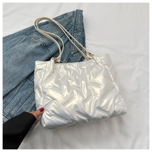 Détail d'un sac cabas blanc matelassé avec finition brillante et coutures chevrons