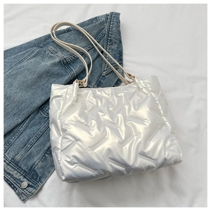 Détail d'un cabas matelassé blanc style doudoune avec finition brillante et anneaux dorés
