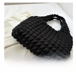 Macro view of black bubble textured fabric and pleated design on a minimalist tote bag