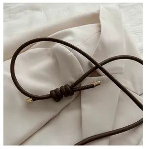 Detail of a brown leather shoulder strap with golden metal caps and decorative knot