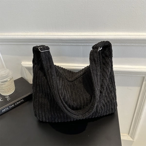 Detail of black corduroy hobo bag showing thick ribbed texture and adjustable metal buckle