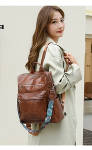 Detail of vintage brown leather backpack showing bohemian printed strap and side pockets
