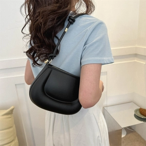 Sac à bandoulière noir minimaliste avec bandoulière nouée et anneau doré sur un mannequin