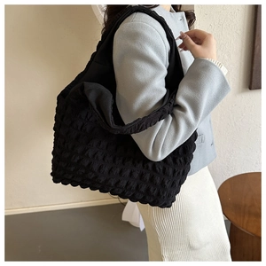 Detailed close-up of a black ruched bubble tote bag with a textured polyester fabric finish