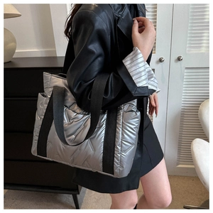 Detail of silver quilted tote bag with metallic finish and black nylon shoulder strap
